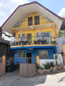 a yellow and blue house with a balcony at Baguio Camella Big Brother House in Baguio