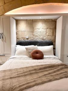 ein Schlafzimmer mit einem großen Bett und einer Steinmauer in der Unterkunft MCC Argotti House in Floriana