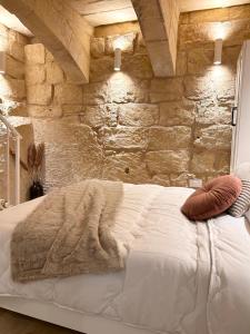 a bedroom with a white bed with a stone wall at MCC Argotti House in Il-Furjana