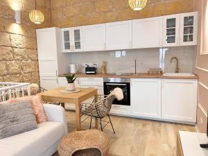 a kitchen with white cabinets and a table and a couch at MCC Argotti House in Il-Furjana