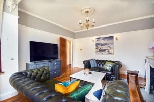 sala de estar con sofá de cuero y TV en Large London home with Free parking, en Winchmore Hill
