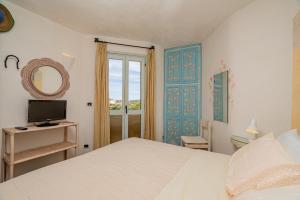 Un dormitorio con una cama y un televisor y una ventana. en Casa Lilly by Wonderful Italy, en Porto Cervo