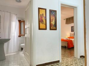 een badkamer met twee foto's aan een muur met een toilet bij Marini Apartment by Diddoi in Marina di Mancaversa
