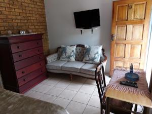 um quarto com um sofá, uma mesa e uma televisão em Lushof Guesthouse em Witbank