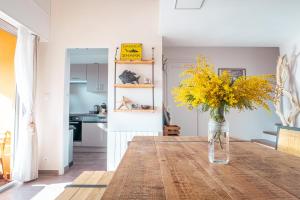un vase de fleurs jaunes assis sur une table dans une cuisine dans l'établissement L'Odyssée provençale, un duplex de charme de 2 chambres au pied du village médiéval de Bormes-les-Mimosas, offrant des prestations haut de gamme et une superbe vue sur le Massif des Maures, à Bormes-les-Mimosas