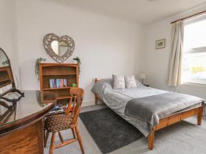 1 dormitorio con cama, escritorio y espejo en Victoria Court, en Weymouth