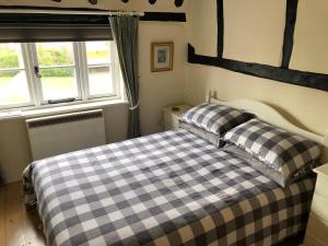 Ludham的住宿－Bakers Cottage Ludham - Norfolk Broads，一间卧室设有两张床和窗户。