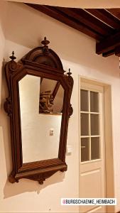 un miroir suspendu sur un mur à côté d'une porte dans l'établissement Burg Zimmer auf ca. 70 m², à Heimbach