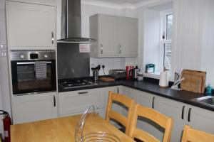 a kitchen with white cabinets and a table and chairs at Beautiful house on NC500 Route in Wick