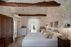 ein Schlafzimmer mit einem großen weißen Bett in einer Steinmauer in der Unterkunft Agriturismo Masseria Aprile in Locorotondo