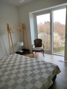 1 dormitorio con cama, silla y ventana grande en Ny bolig i grønne omgivelser. en Rødovre