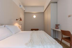 1 dormitorio con cama blanca y escritorio en BePlace Apartments in De Angeli, en Milán