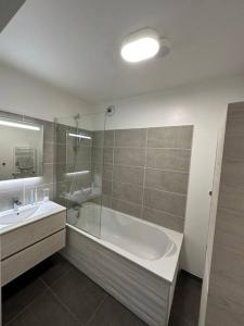 y baño con bañera, lavabo y espejo. en F3 - Standing, idéalement situé, en Ajaccio