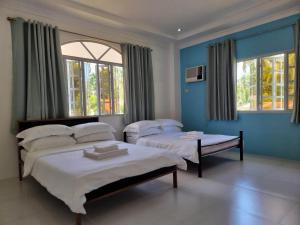 2 camas en una habitación con paredes y ventanas azules en Bretthouse Tourist Inn, en Lila
