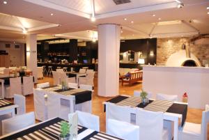 un restaurant avec des tables blanches et des chaises blanches dans l'établissement Hotel Kanelli Beach, à Selianitika
