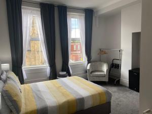 a bedroom with a bed and a chair and two windows at Athol House in South Shields