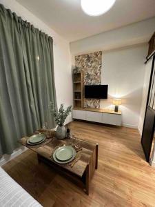 a living room with a table and a television at Le P’tit Antoine in Pont-lʼÉvêque +3 photos