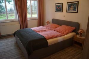 a bed in a bedroom with two windows at Landhaus Eickhof in Niederhaverbeck