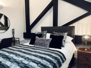 a bedroom with a black and white bed with pillows at EXCLUSIVE and MODERN - Bradford City Centre- 85" Cinema TV in Bradford