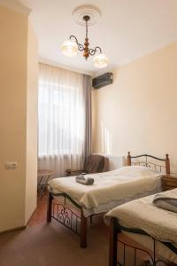 a room with two beds and a chair and a window at Tamari Guest House in Tʼelavi