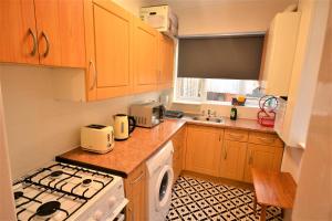 a kitchen with wooden cabinets and a stove top oven at Lovely 3 Bedroom House near Barking Station in Barking
