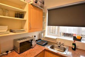 a kitchen with a sink and a microwave at Lovely 3 Bedroom House near Barking Station in Barking
