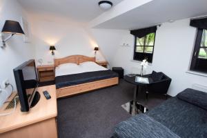 a bedroom with two beds and a desk with a television at Pension Ari am See in Ostseebad Sellin
