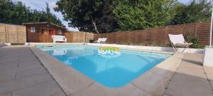 a swimming pool with blue water in a backyard at Studio atypique avec Piscine à partager en option in La Ferté-Gaucher