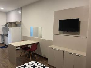 uma cozinha com uma mesa e uma televisão na parede em Flat Aconchegante em Sorocaba