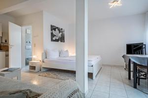 a white bedroom with a bed and a table at Fewo Eg Rechts - Hunde erlaubt in Oberteuringen