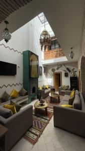 RIAD LUXE LOCATION le GRIZZLY في مراكش: غرفة معيشة كبيرة مع كنب ومدفأة