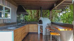 an outdoor kitchen with an outdoor oven and stools at Casa com piscina e vista para o mar em Ilhabela in Ilhabela