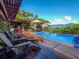 a pool with chairs and a table and an umbrella at Casa com piscina e vista para o mar em Ilhabela in Ilhabela