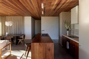 a kitchen and dining room with a wooden ceiling at Sister's Sanctuary in Raglan