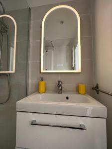 bagno con lavandino bianco e specchio di Appartement hyper centre de Cabourg avec balcon a Cabourg