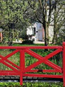 a red fence in front of a white house at La mare aux petits diables in Équemauville