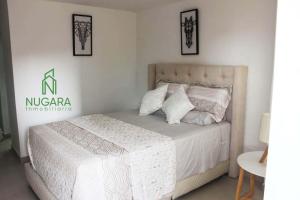 um quarto com uma cama com lençóis brancos e almofadas em Apartamento Super-Confortable em Zipaquirá