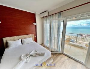 a bedroom with a bed and a balcony with the ocean at Blumont Aparthotel Durres in Durrës
