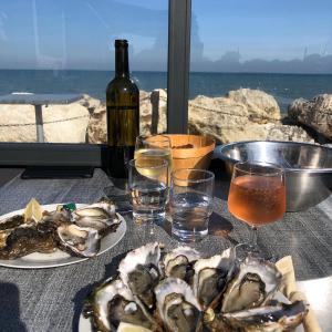 - une table avec deux assiettes d'huîtres et une bouteille de vin dans l'établissement Les pois sont verts, à La Rochelle
