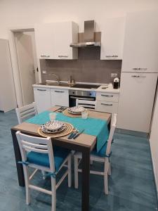 y cocina con mesa de madera, sillas y fogones. en Villa Maria - Capri House Vista Mare, en Monte di Procida