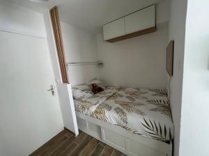 una piccola camera da letto con un letto con un gatto sopra di Appartement hyper centre de Cabourg avec balcon a Cabourg