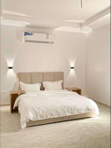 a white bedroom with a bed and two lamps at Luxury and Modern Apartments in Mudhainib in Al Madinah