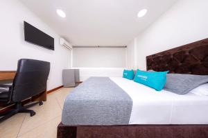 a bedroom with a bed and a desk and a chair at Hotel Ayenda Palo Alto in Medellín