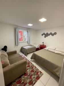 a hotel room with two beds and a couch at Social Hostel Café e Bar in Curitiba