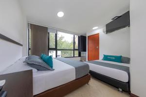 1 dormitorio con 2 camas y ventana en Hotel Ayenda Palo Alto, en Medellín