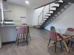 a room with a table and chairs and a staircase at O Recuncho de Domingos in Brion de Abajo
