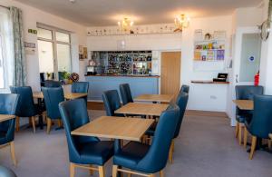 un restaurante con mesas de madera y sillas azules en The Shelbourne en Llandudno