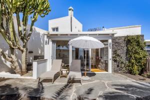 a white house with two chairs and an umbrella at Apartamento Lanzarote Art Suite 3 in San Bartolomé