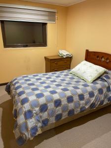 um quarto com uma cama com um cobertor xadrez azul e branco em Casa Sra Oti em Puerto Montt