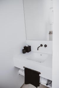 uma casa de banho branca com um lavatório e uma cadeira. em Visite em Evergem